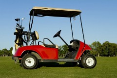 a red golf cart and golf clubs on a golf course